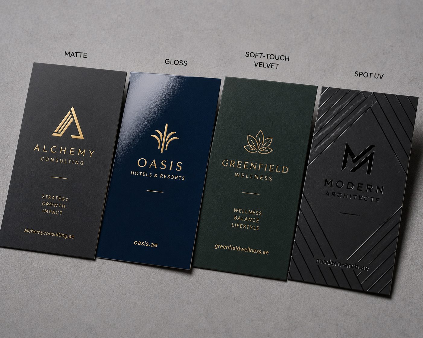 Several business cards side by side showing different finishes — matte, gloss, soft-touch velvet and spot UV — fanned on a neutral surface