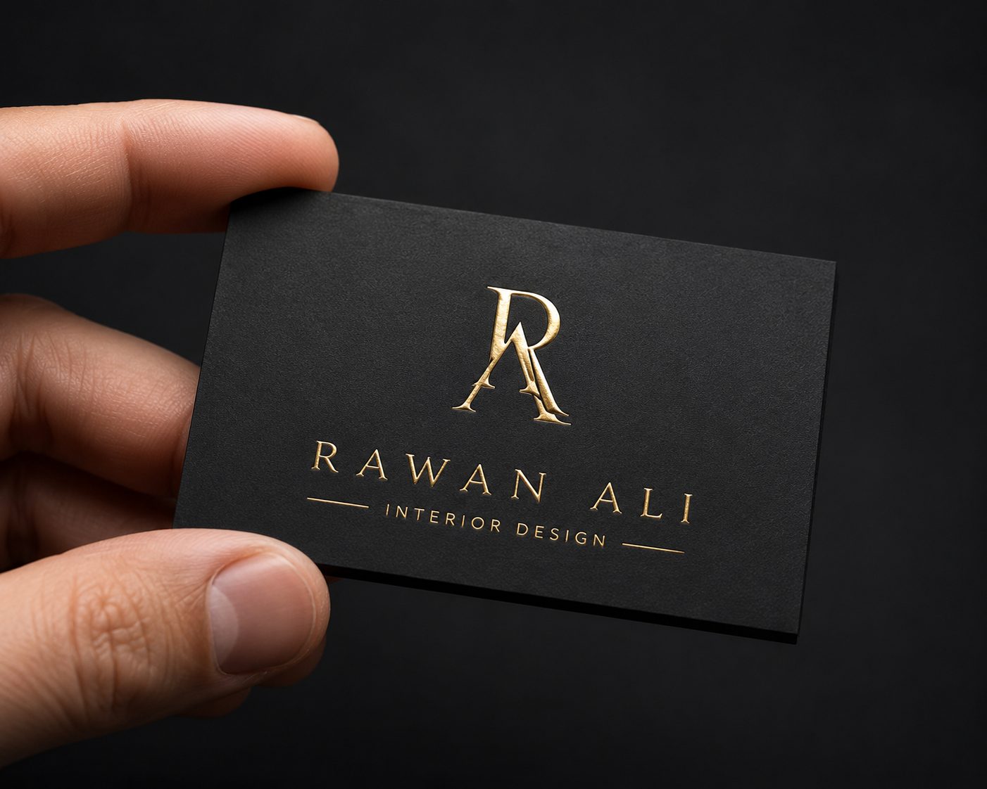 A premium matte black business card with a gold-foil logo held between two fingers, showing the foil shine and 400gsm thickness, soft studio light